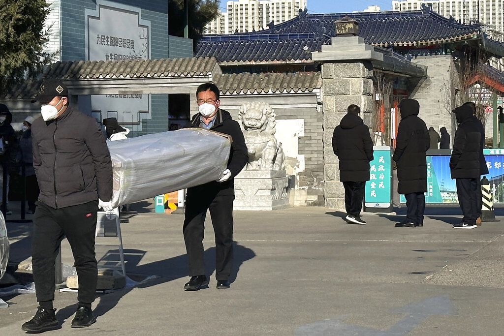 2022年12月17日，两名男子在北京的某火葬场外抬着棺材。 (AP / Ng Han Guan)