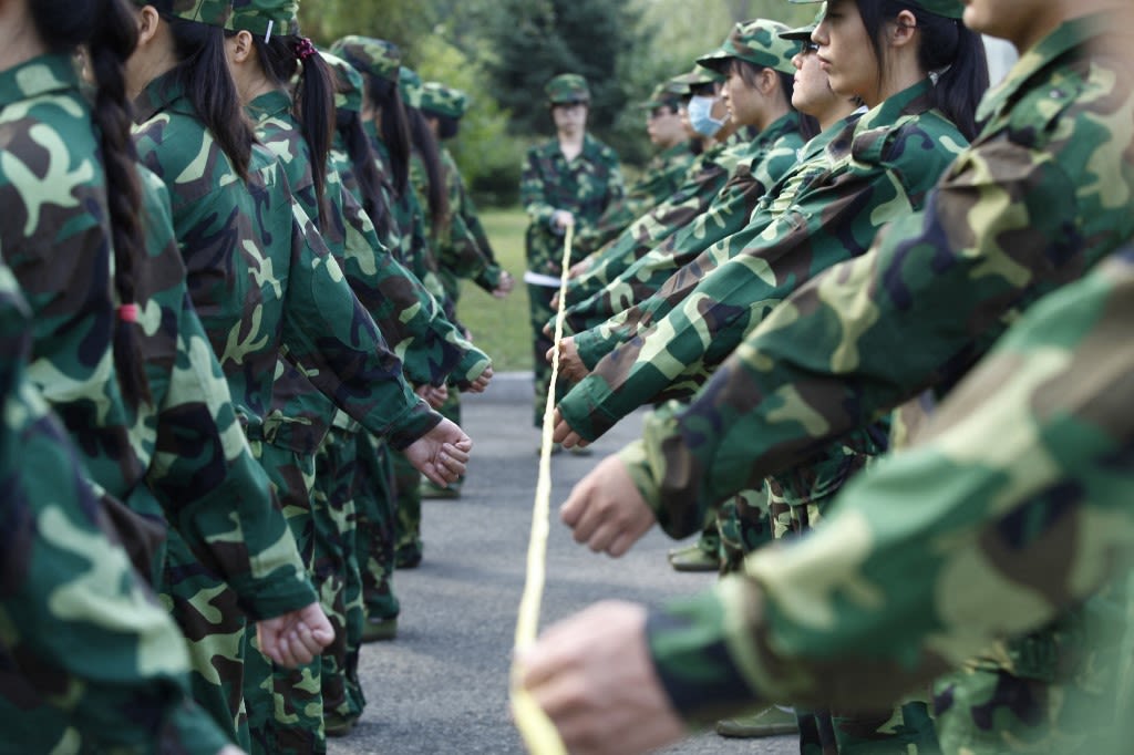 2014年9月2日，黑龙江省哈尔滨市一所大学校园内，参加军训的学生在教官的“标尺”下训练踢正步。（ AFP）