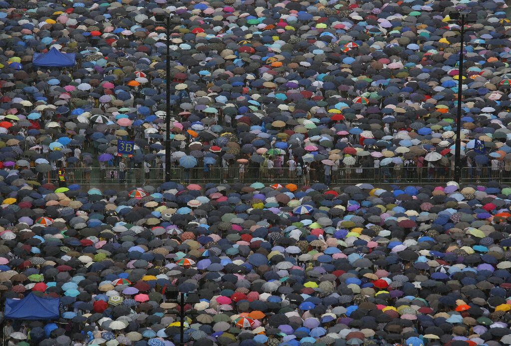 2013年7月1日，香港抗议者在暴雨中撑伞游行。一个台风当时正接近香港，这是七一游行首次在狂风暴雨中举行，但糟糕的天气并未阻止香港人走上街头。当年游行有多数诉求都是针对特首梁振英，指责他上任以来未能兑现承诺且诚信有问题，并要求他下台。(AP/Vincent Yu)