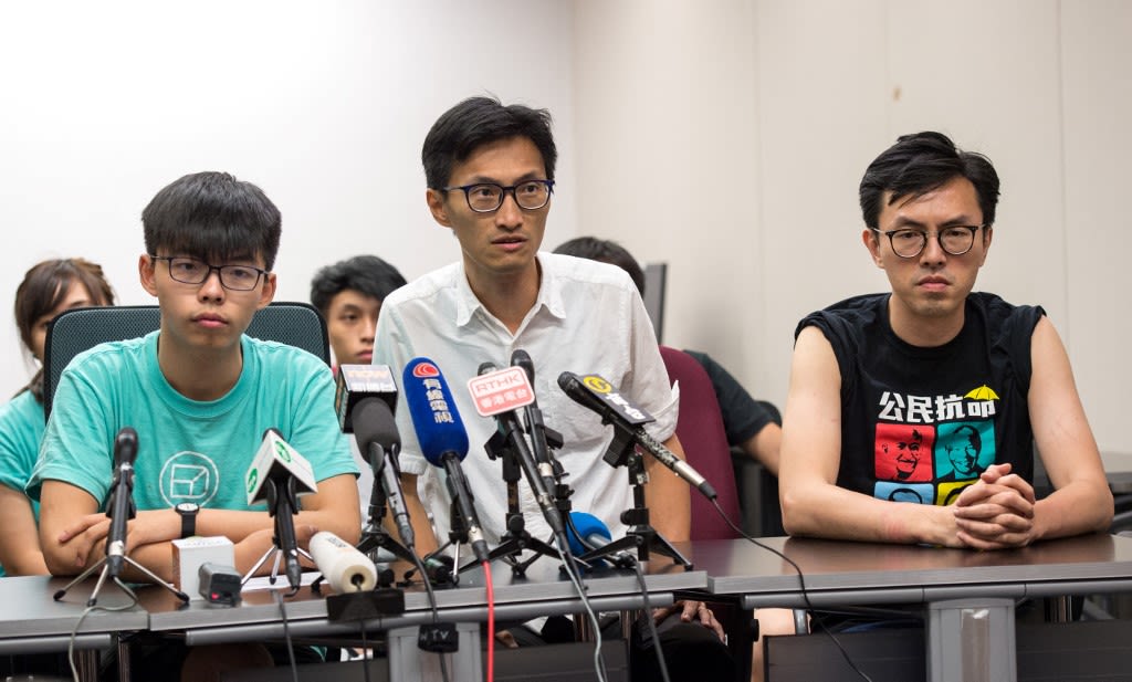 2017年7月1日，就在习近平与林郑会面同日，香港民运人士黄之锋（左）、朱海迪（中）和吴艾利（右）出席在香港举行的新闻发布会。当日，黄之锋被香港警方以“保护”为由，被戴上手铐并带走。（AFP/Jayne Russell ）