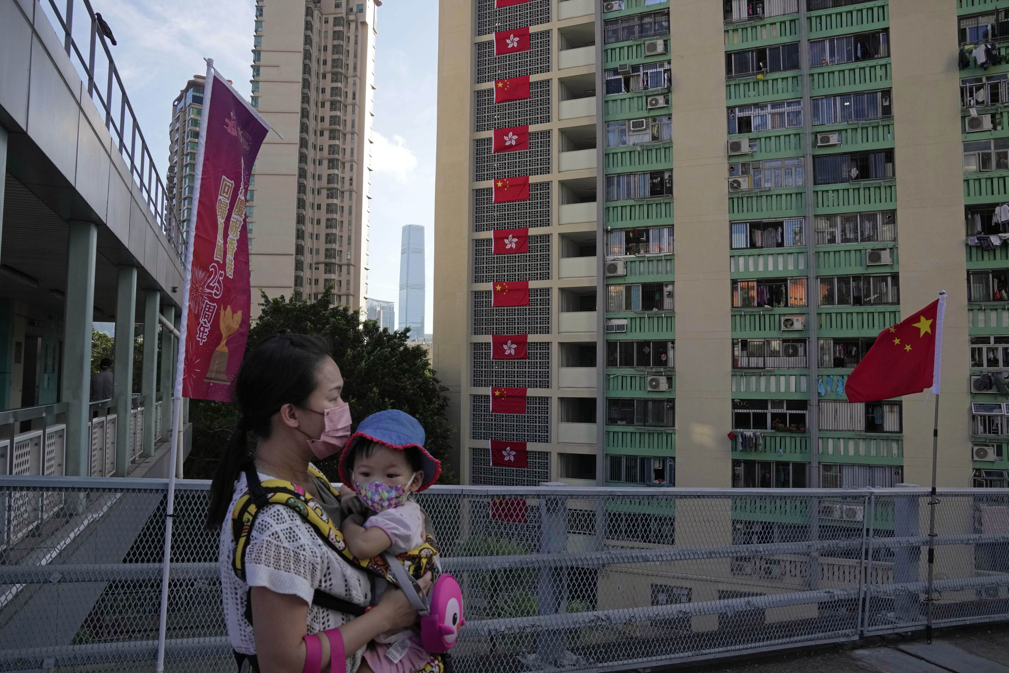 历年来官媒的宣传，香港积累了不少“深层次矛盾”，而其一直未获有效解决。图为香港公屋前飘荡的中国与香港区旗与路经的民众。 (AP Photo/Kin Cheung)