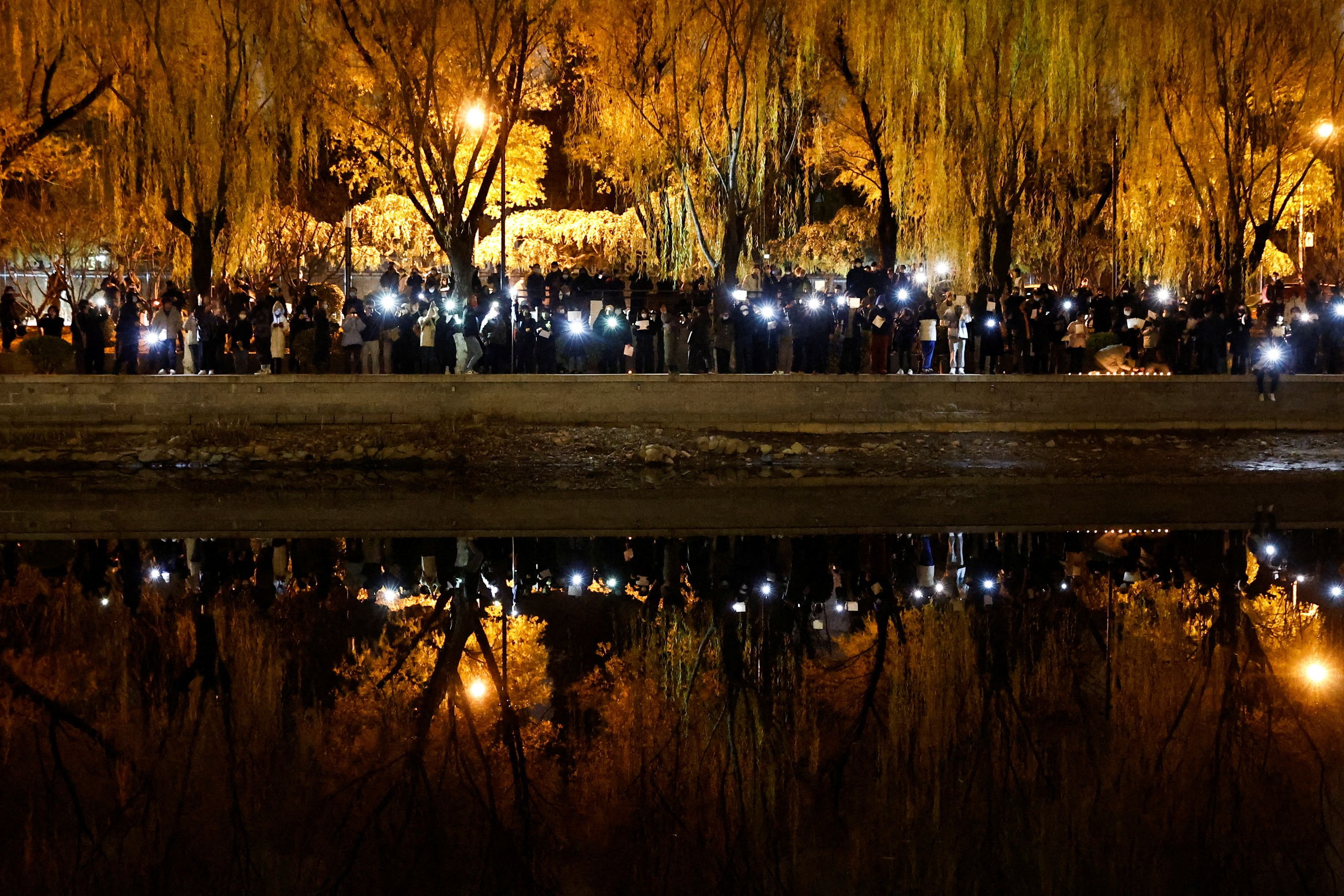 November 27, 2022, people gather along Liangma River in Beijing to commemorate the victims of the Urumqi fire. (REUTERS / Thomas Peter)