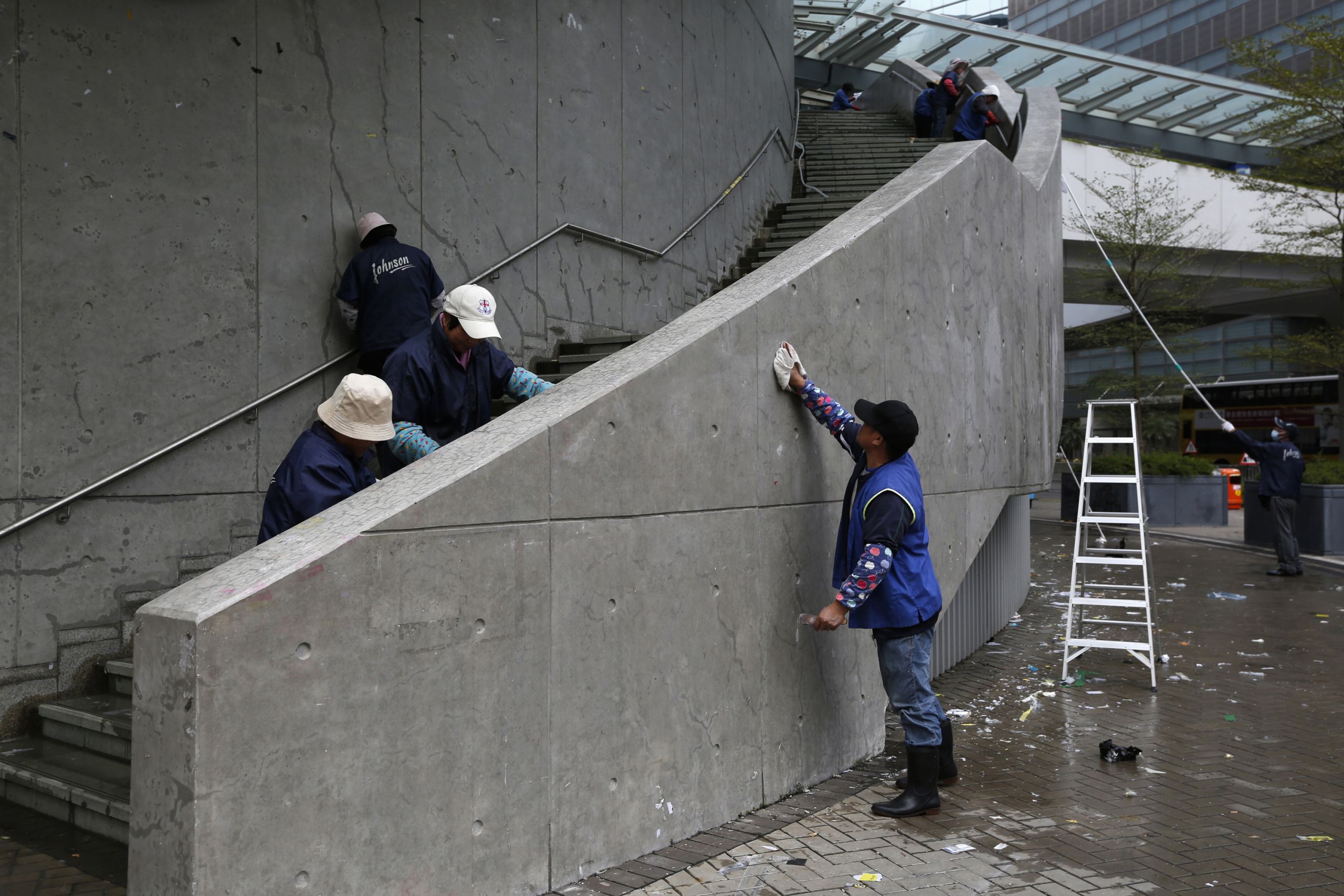 Workers clean up the "Lennon Wall" outside government headquarters where thousands of colorful notes written by pro-democracy supporters were displayed, marking an end to more than two months of street demonstrations in Hong Kong. 
