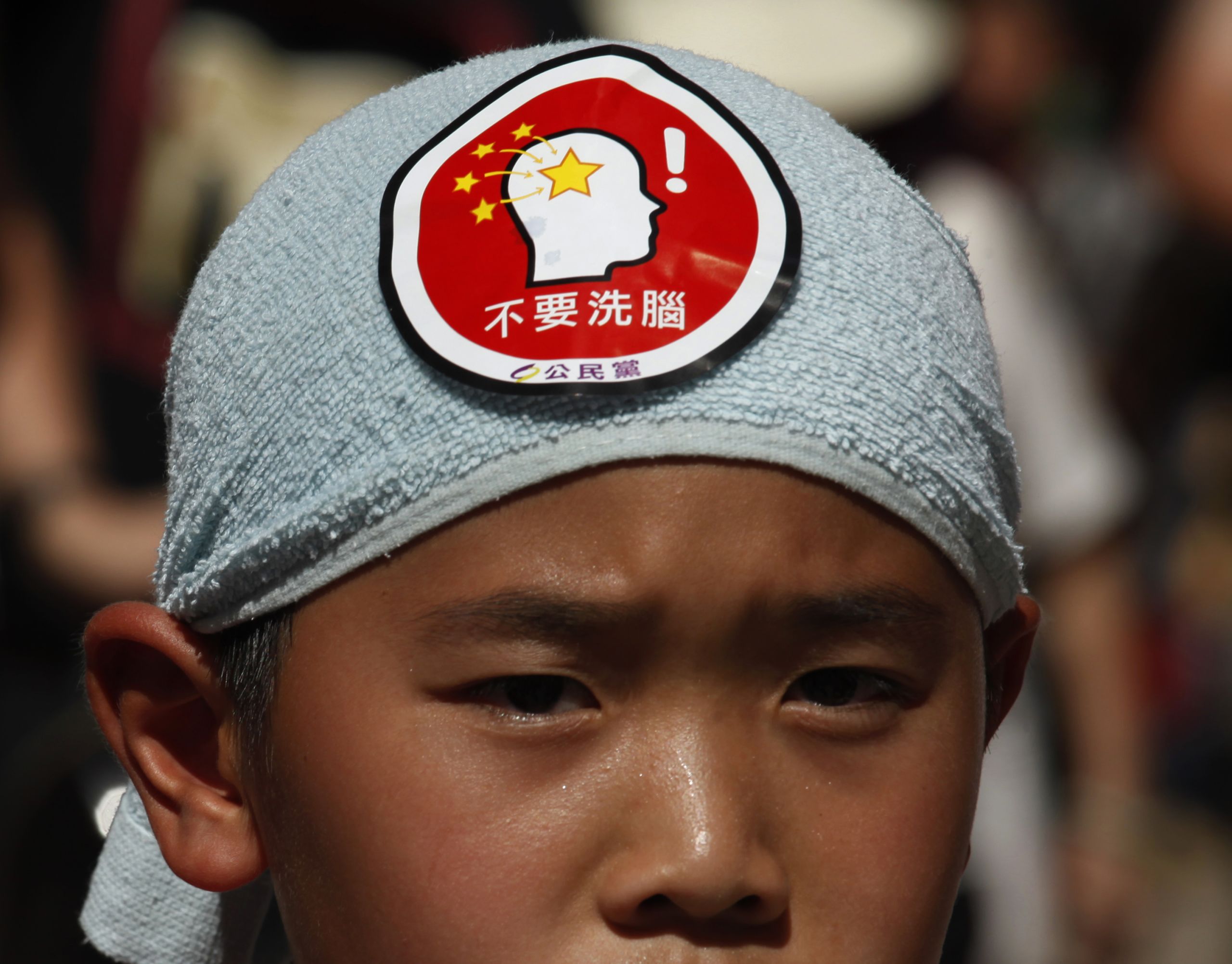 2012年的「全民行動，反對洗腦」，7月29日，萬人大遊行中，一名示威兒童頭戴寫有“不要洗腦”字樣的標籤。 （圖：Reuters）