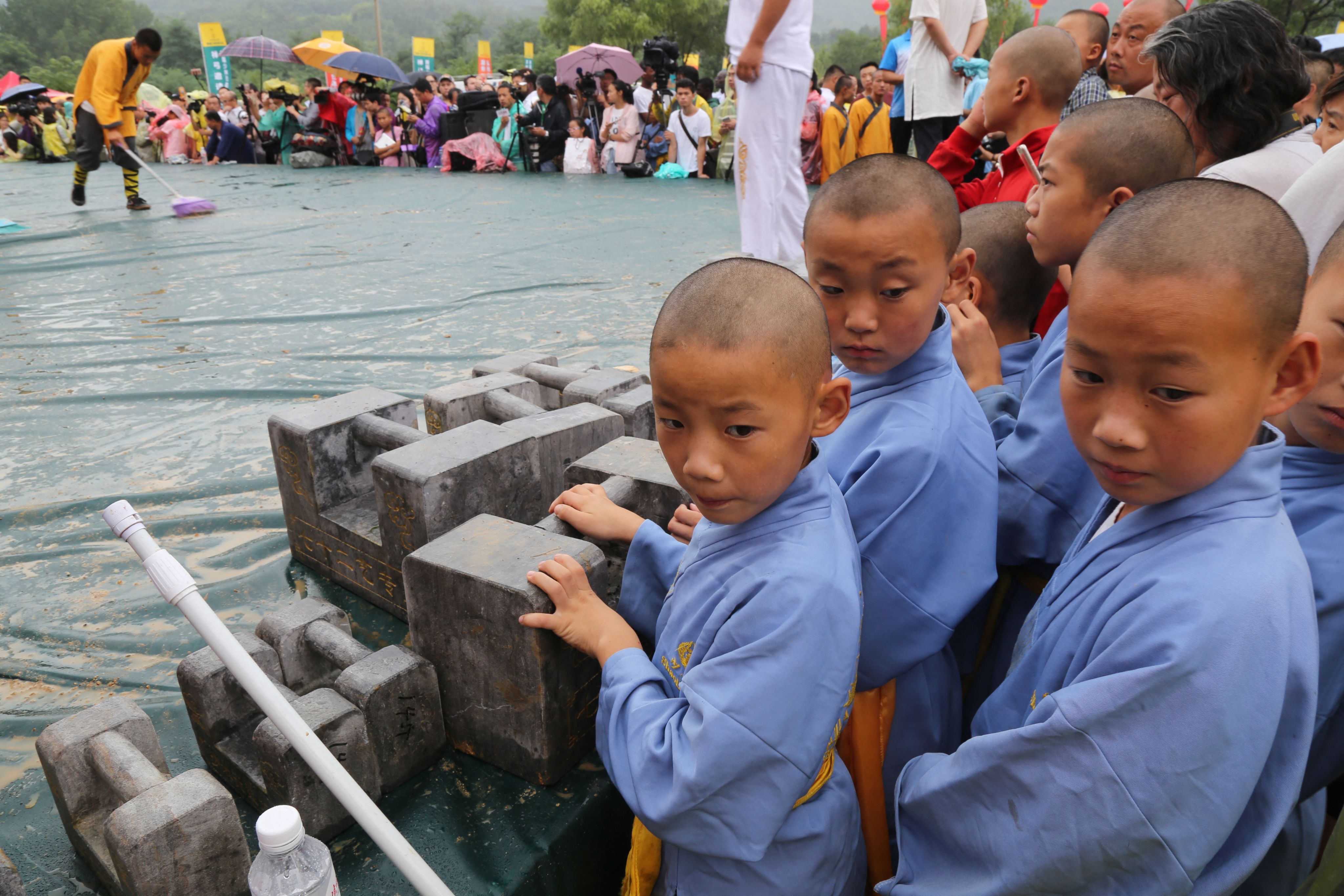 2017年7月30日，河南省登封市少林寺举行的首届“少林七十二式”武术比赛中，年轻的少林僧人在石锁旁观看。