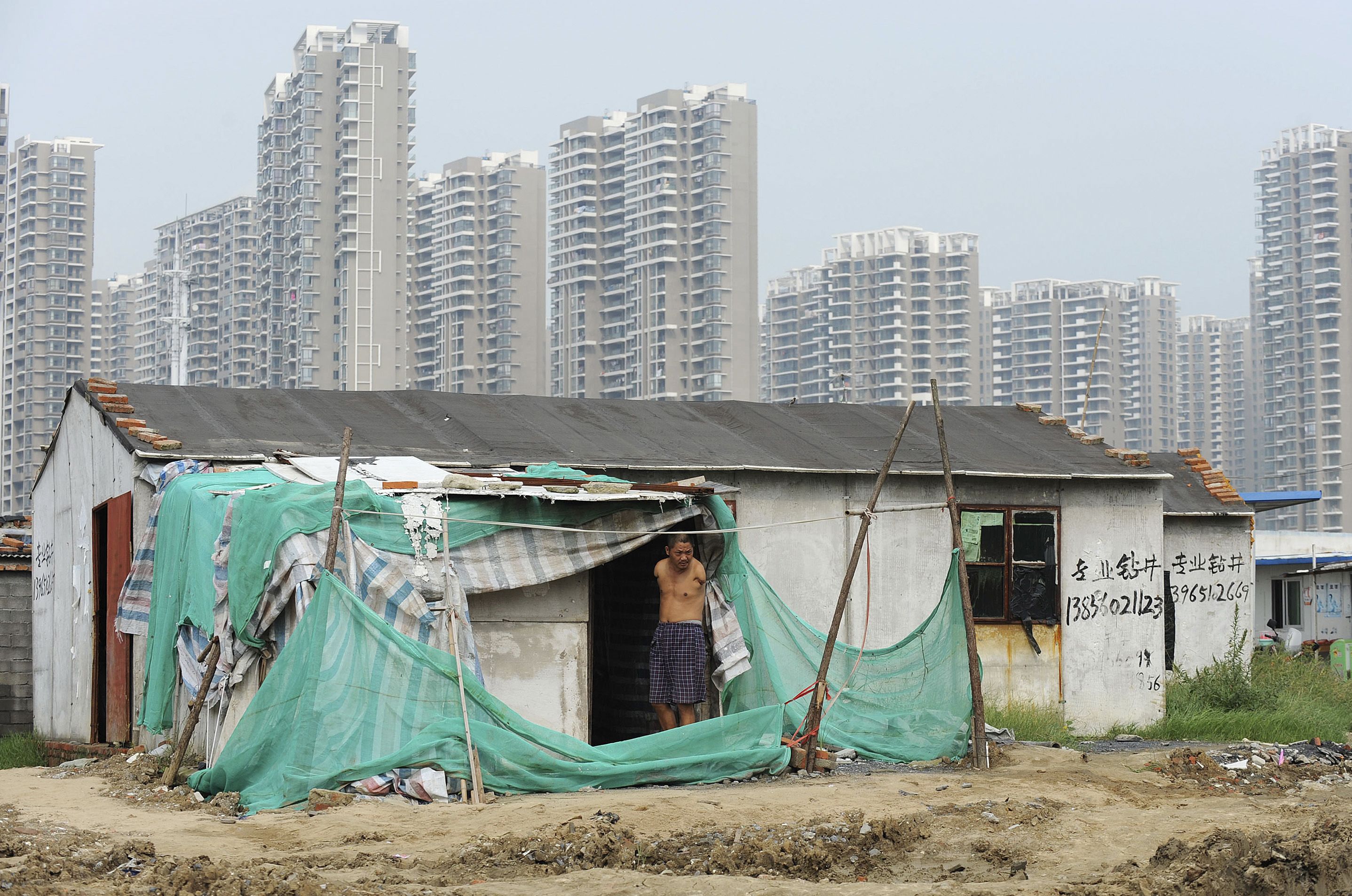 安徽省合肥市，一名失去双臂的残疾人站在自己居住的简易建筑门前。（REUTERS）