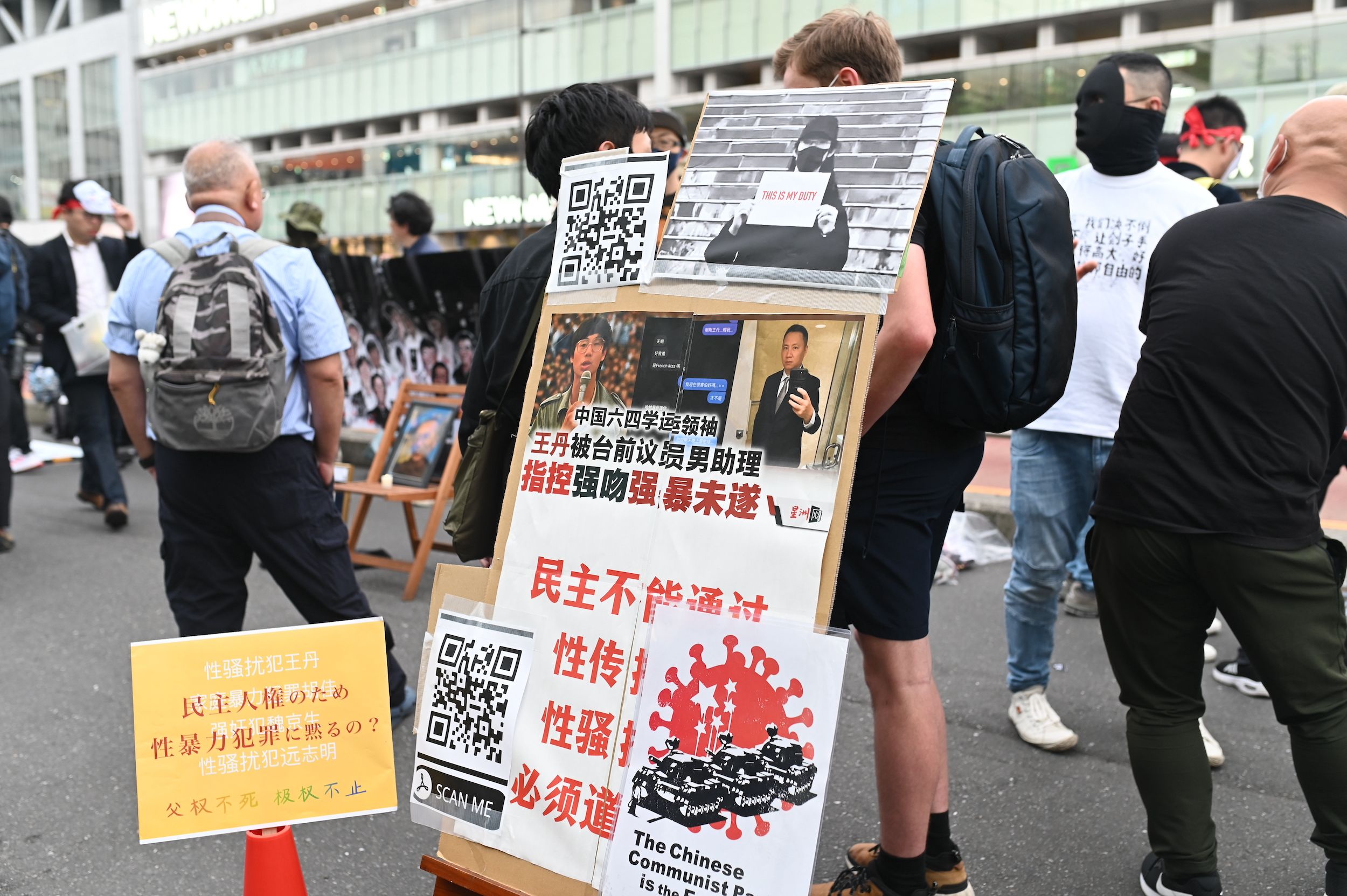 一个牌子对王丹的问责和抗议，上面写着：“民主不能通过性传播！性骚扰犯必须道歉！”