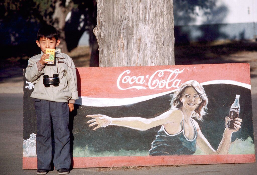 1985年11月1日，北京，一个男孩在可口可乐的“充满洋味儿”的广告牌前。(AP / Neal Ulevich)
