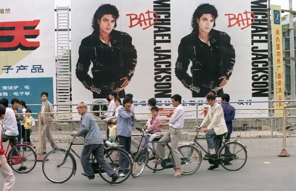 1989年6月11日，上海，人们经过几张迈克尔·杰克逊的巨型海报。1987年，迈克尔·杰克逊的专辑《Bad》第一次被引进中国。 (AFP)