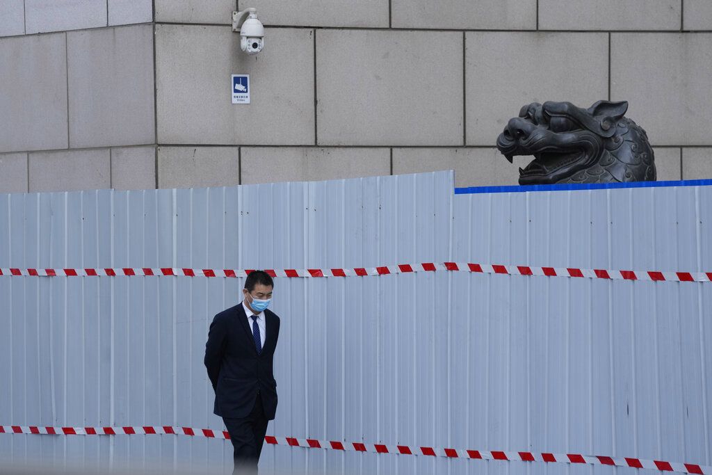 2022年4月20日，北京，一名戴着口罩的工人走过被围拦封闭的购物中心。 (AP / Ng Han Guan)