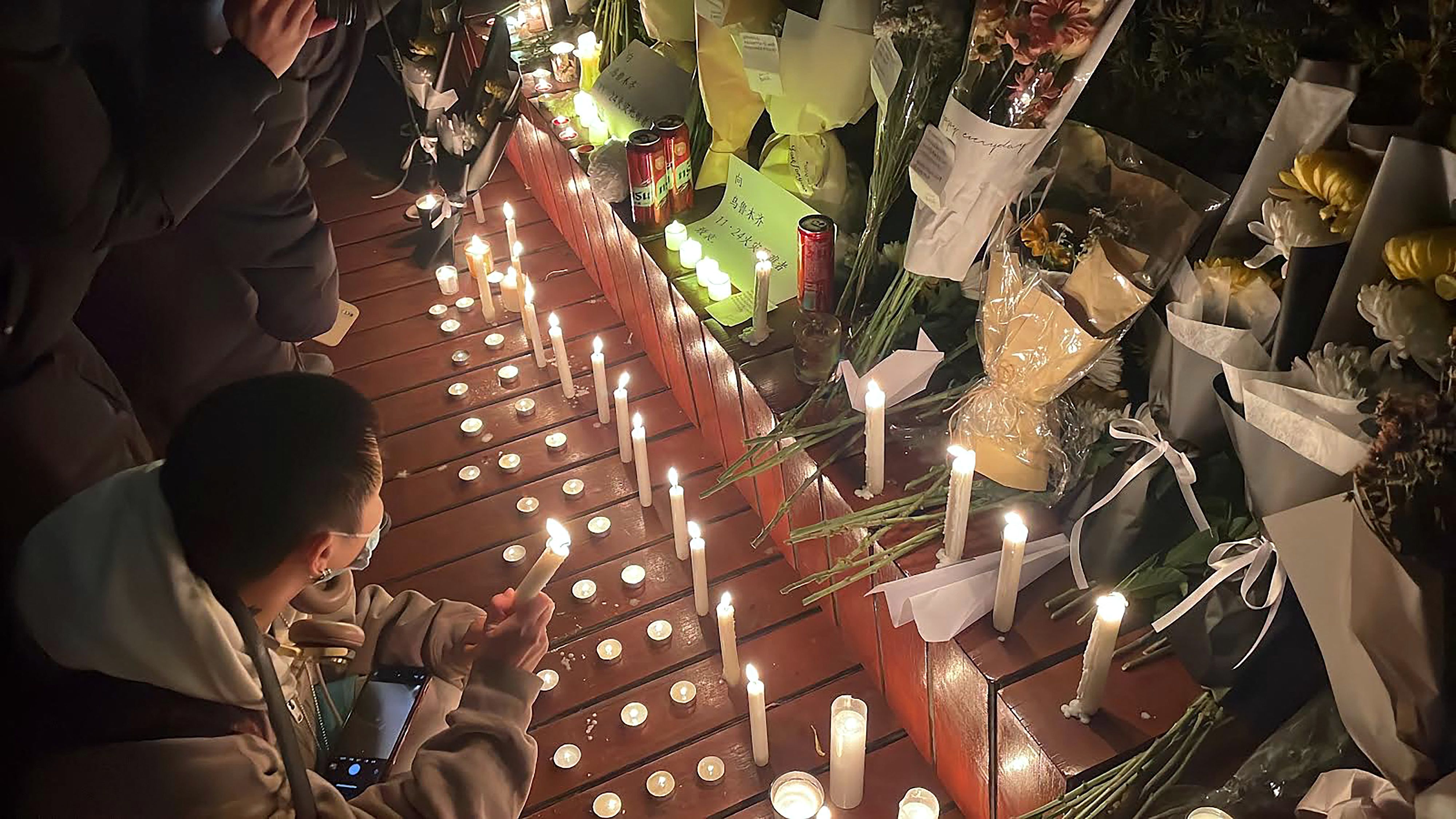 11月28日2022年，北京人民为乌鲁木齐火灾的遇难者聚集摆放蜡烛和鲜花在街道上守夜。 (AFP / Michael Zhang)