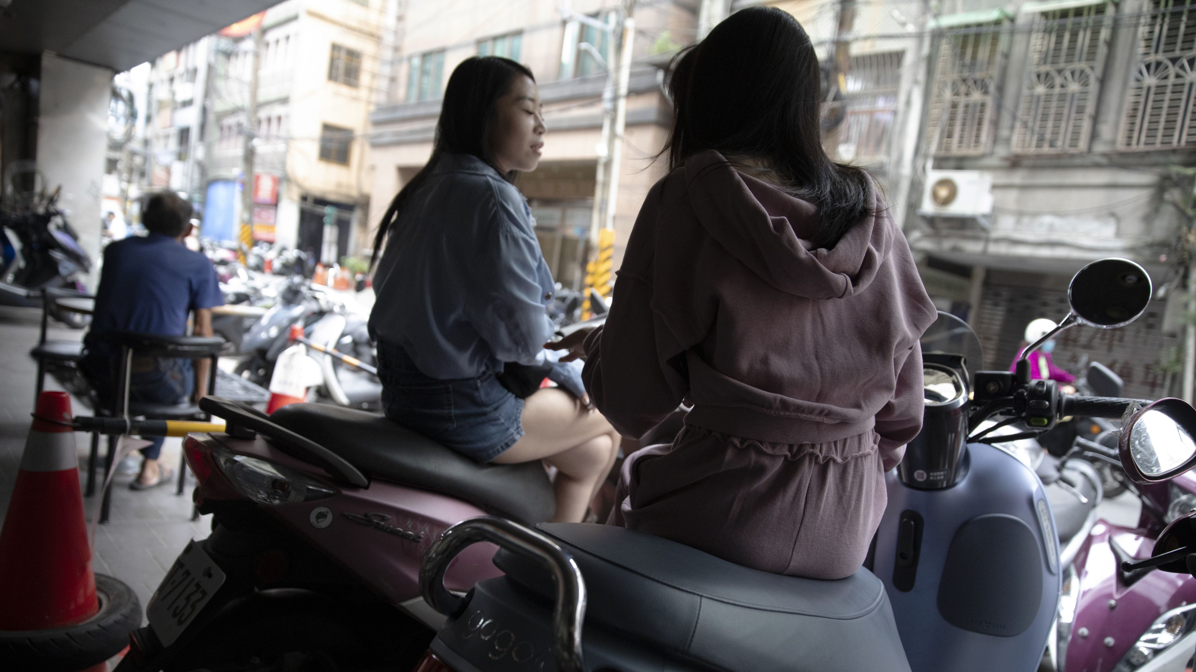 基隆街道旁，坐在机车上的年轻女性。