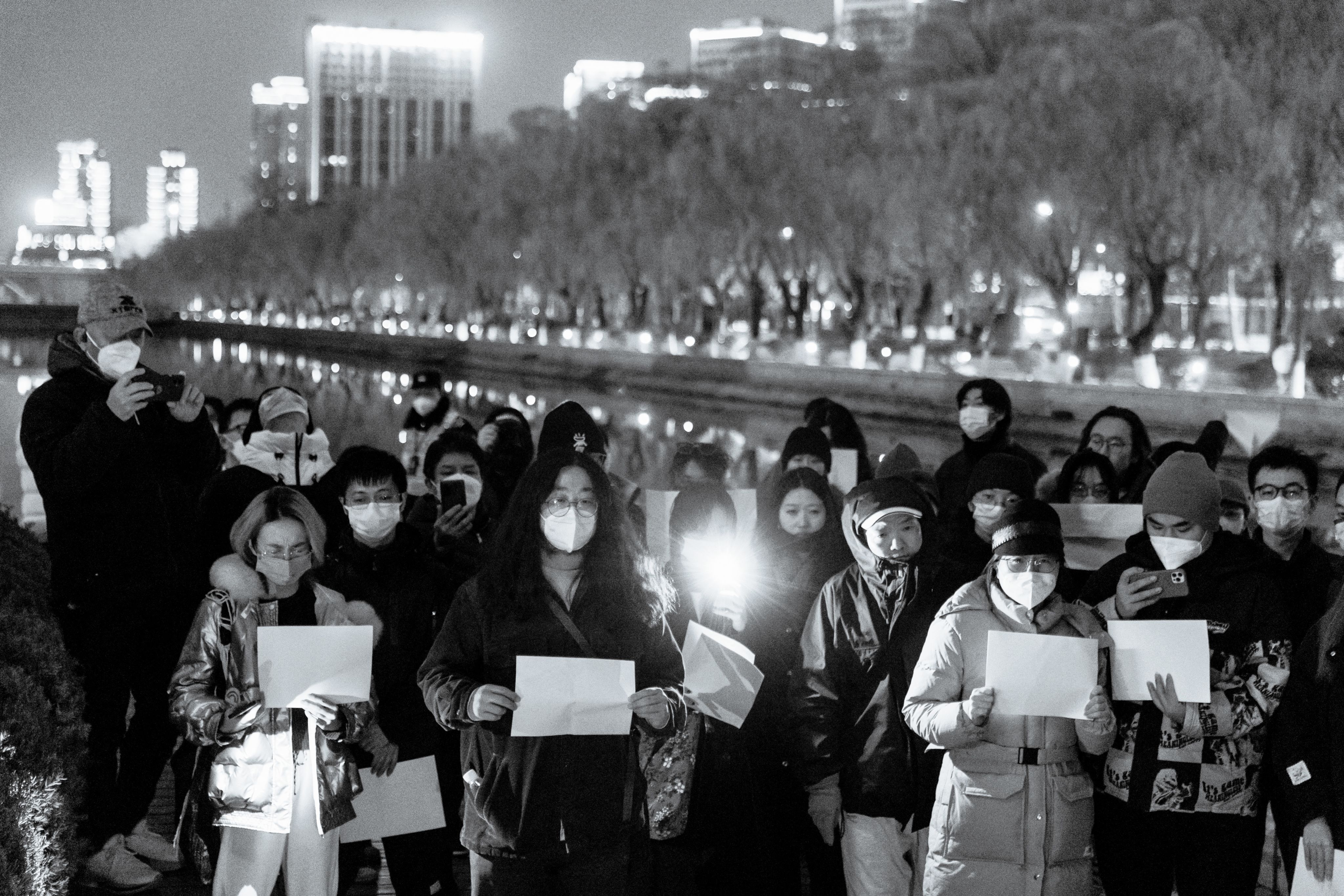 November 27, 2022, people hold blank pieces of paper in protest against COVID-19 lockdown policies along the Liangma River in Beijing, China. (REUTERS / Thomas Peter)