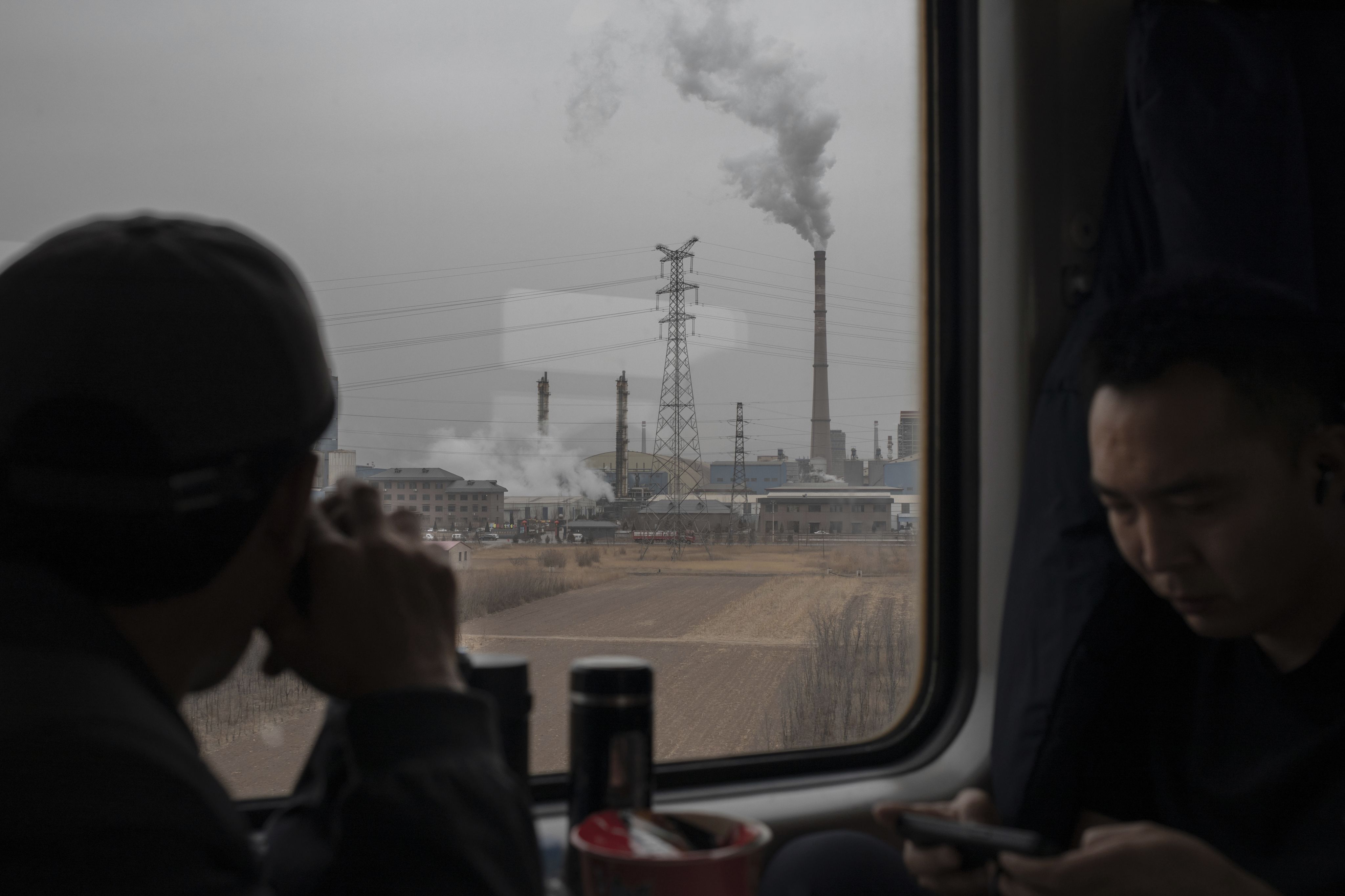 太原到汾阳靠近汾阳段的铁路上，硬座车厢中的乘客望着窗外成片的工厂