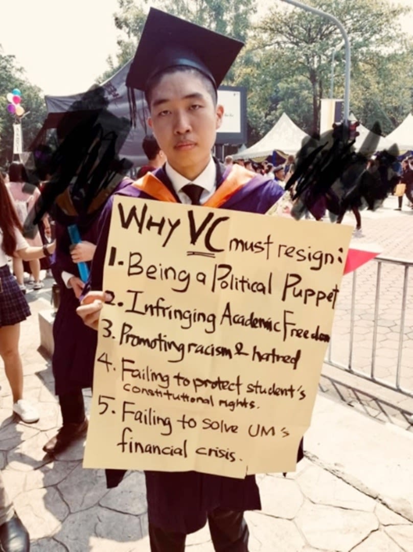 身穿毕业袍的黄彦铬在毕业典礼台上展示大字报