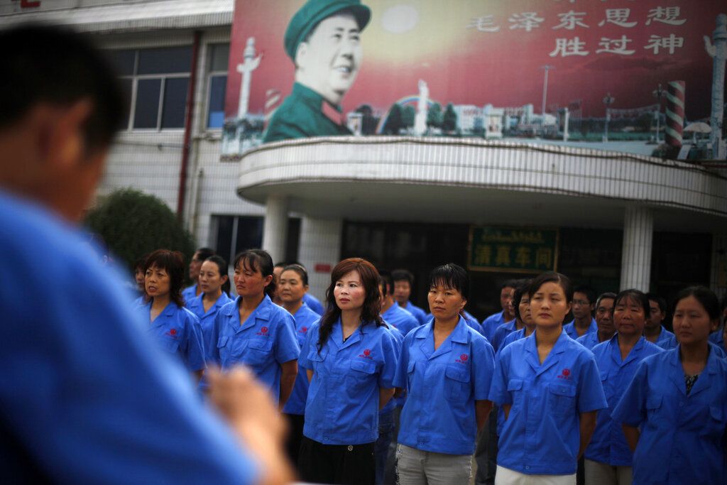 2009年8月26日，河南漯河市南街村，村办企业工人们在“毛像”前合唱革命歌曲，准备开始一天的工作。 (AP/ Elizabeth Dalziel)