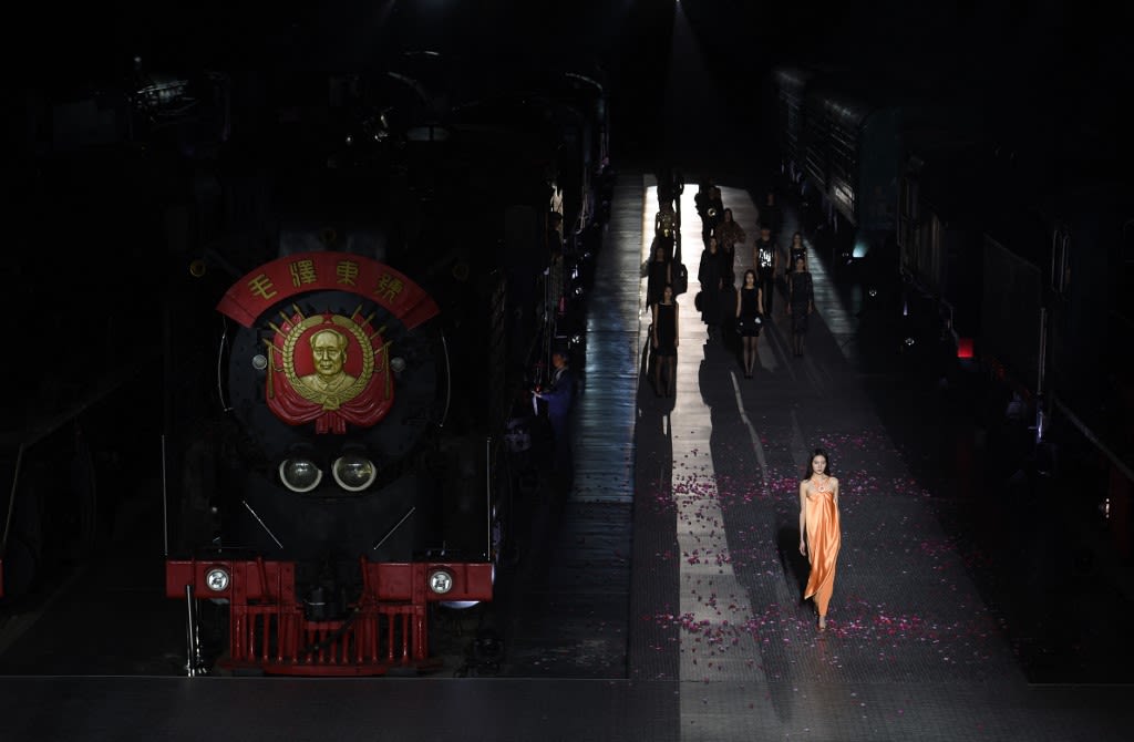 2015年10月20日，在北京中国铁路博物馆举行的时装秀上，模特们身着皮尔卡丹 2016 春夏系列的时装，在一辆挂有“毛泽东像”的火车旁走秀。这是一次资本主义与“革命”的碰撞。 (AFP / Greg Baker)
