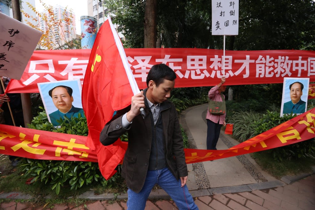 2013年1月9日，广州市，南方报业传媒集团总部门前，一名亲政府人士打出“毛泽东像“和”只有毛泽东思想才能救中国“的标语，与另一批抗议政府加大媒体审查的示威者对峙。