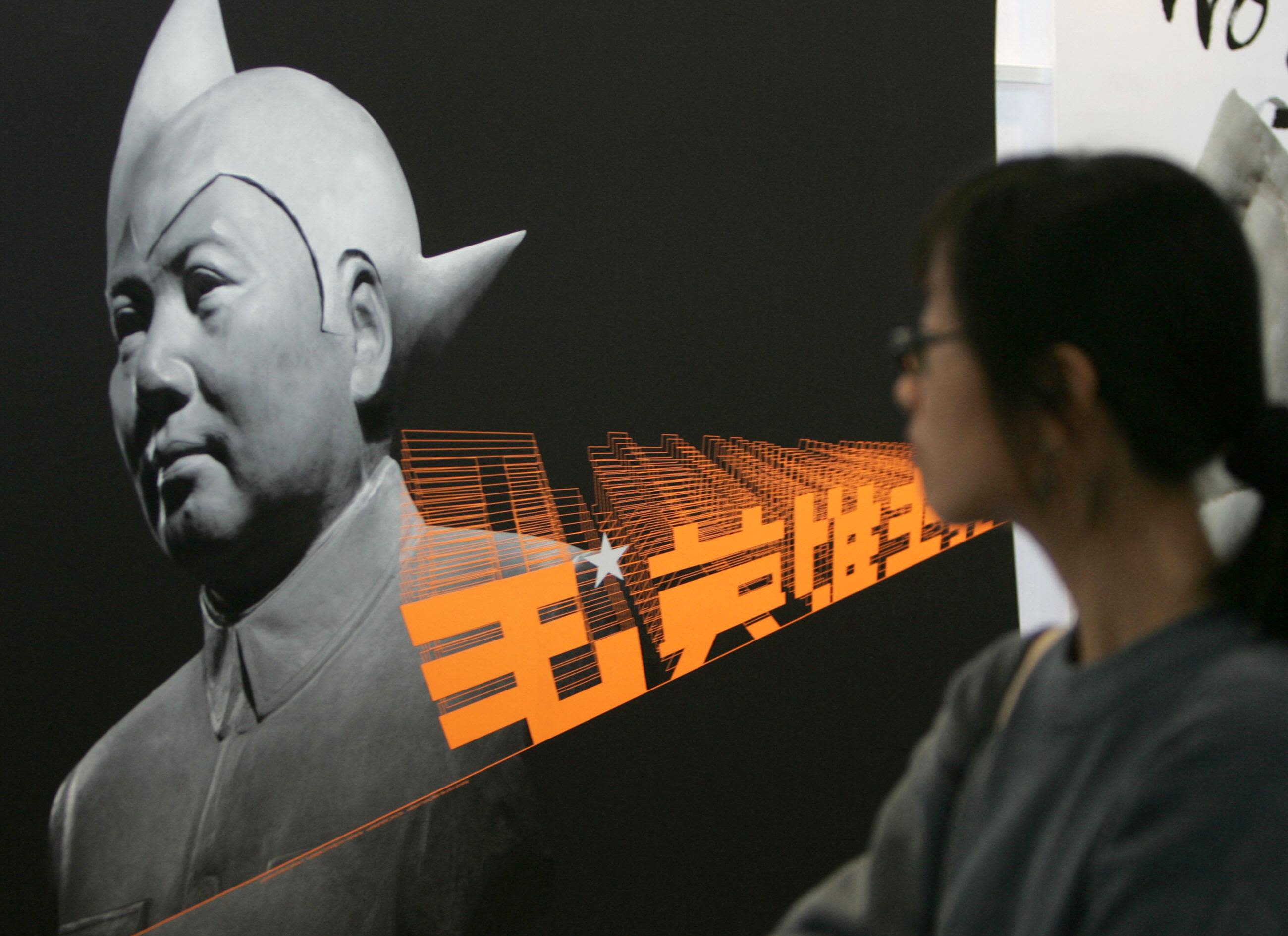 2005年11月21日，在香港会展中心举行的中小型企业 (SME) 博览会上，一名女性正在观看基于毛泽东设计的未来主义肖像。（AFP / Ted Aljibe）