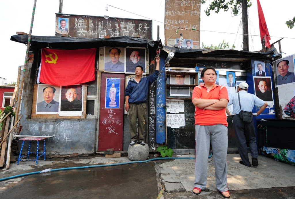 2008年7月15日，北京，一户居民在自家建筑上贴满了“毛泽东像”和其他领导人肖像，来抵制政府对他们的驱逐。他们需要时刻保持警惕，以防随时可能发生的强拆。（AFP / Frederic J. Brown）