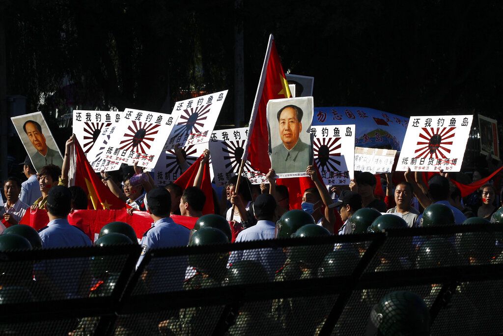 2012年9月18日，北京，日本大使馆门前游行的群众打出“抵制日货”口号和“毛泽东像”，以展示自己的强硬姿态。(AP / Alexander F. Yuan)