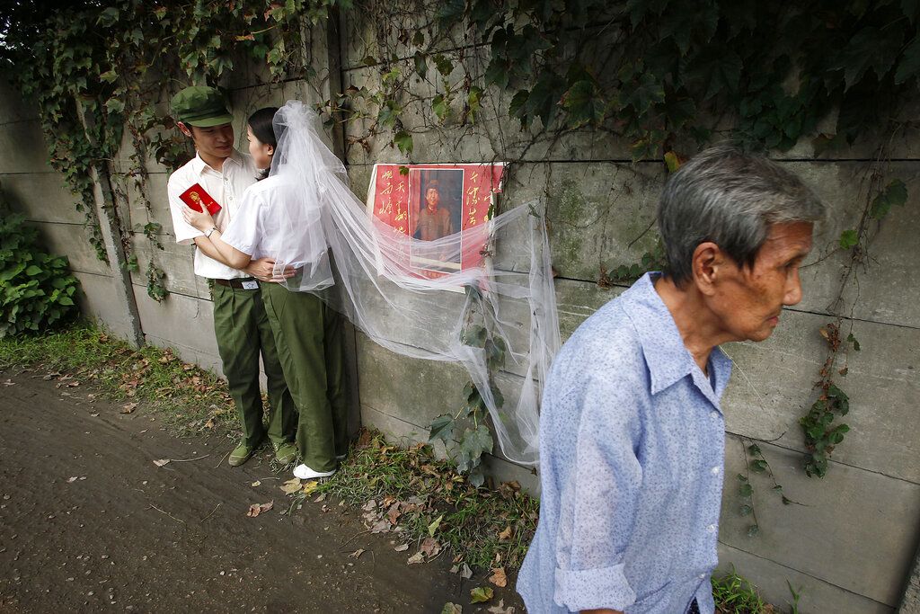2009年8月24日，浙江省杭州市，一对新婚夫妇在“毛像”前拍摄“文革”主题婚纱照。这一主题近年来被一些中国年轻人所认可。 (AP / Eugene Hoshiko)