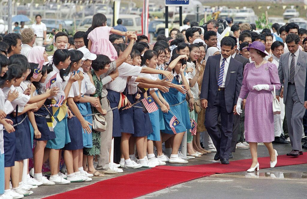 1989年10月16日，英国女王伊丽莎白二世从怡保机场出发前往马来西亚吉隆坡进行国事访问时，受到当地儿童的热烈欢迎。(AP / Russell McPhedran)