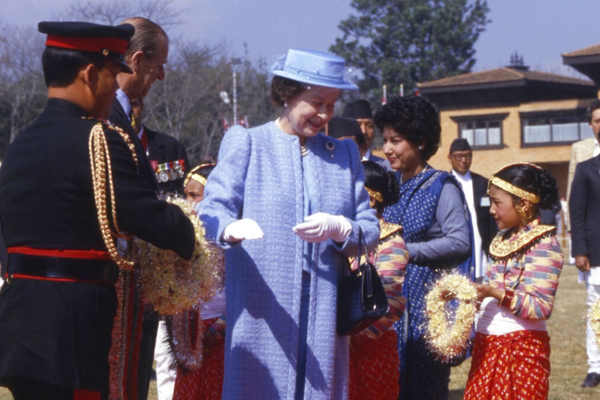 1986年2月21日，英国女王伊丽莎白二世从一名穿着代表加德满都处女女神的尼泊尔女孩手中接过花环。(AP / Peter Kemp)