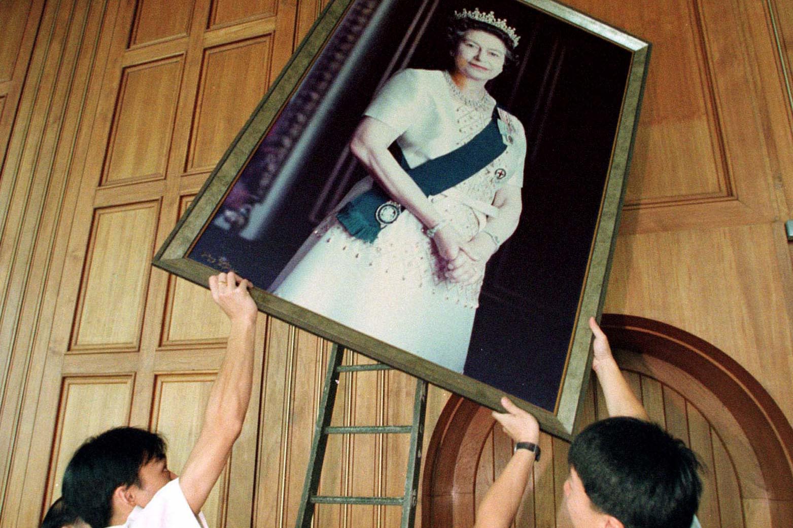 1997年6月16日，香港威尔士亲王军营的中国工人正在移除餐厅里的伊丽莎白二世女王肖像。英国军队将在7月1日离开香港，他们提前两周开始收拾行李。（RFA /Paul Nelson)