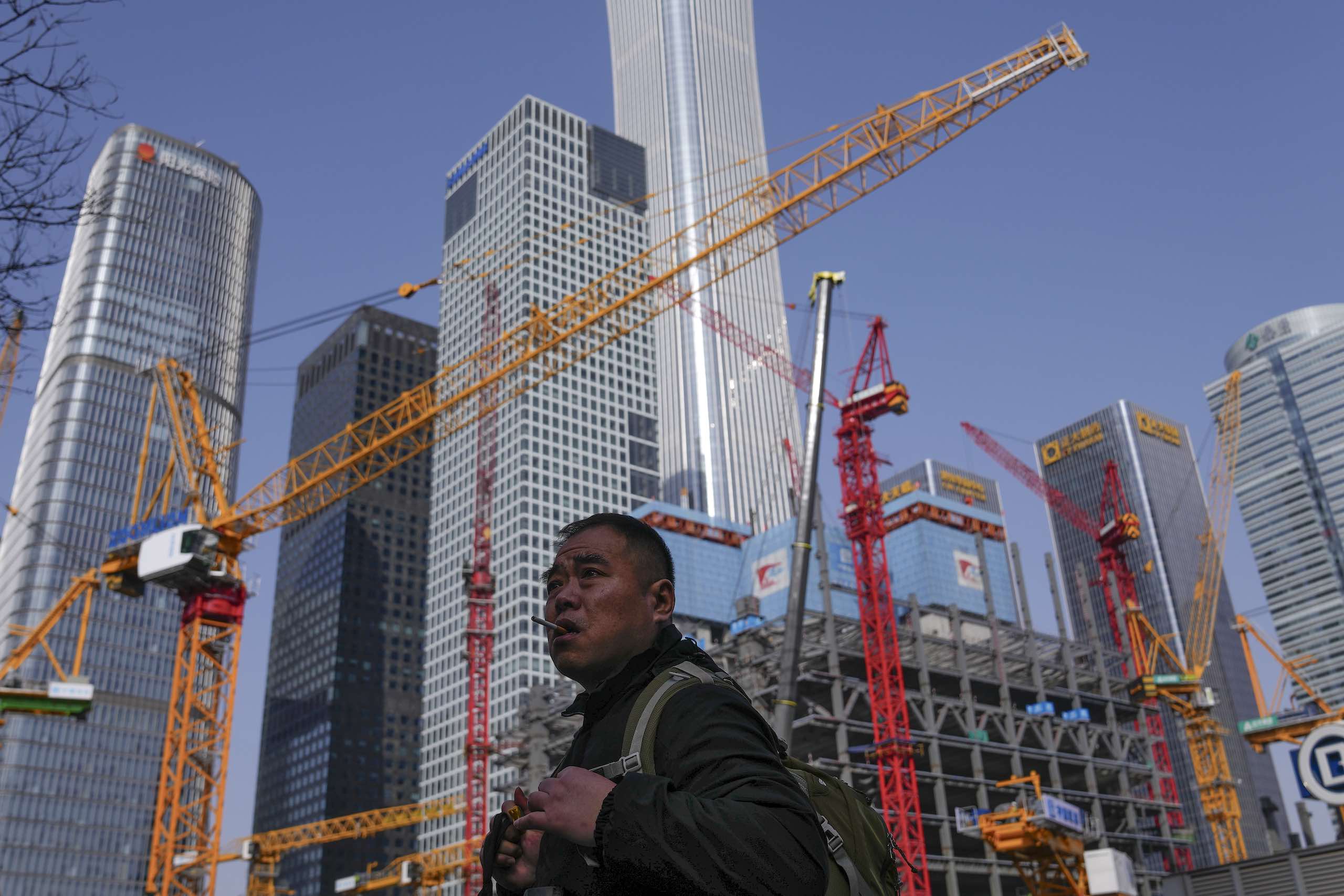 一位农民工走过办公楼附近的建筑工地。