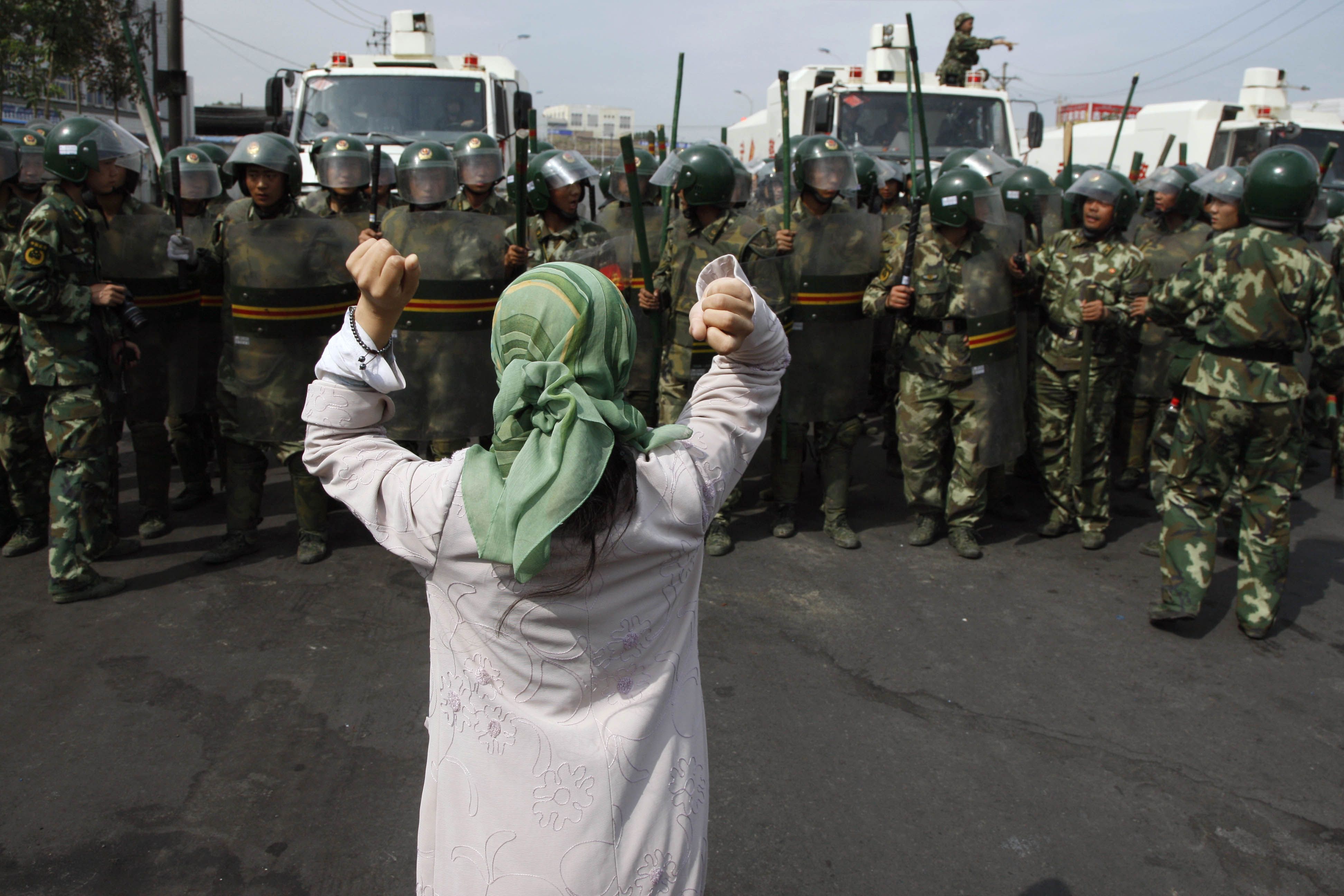 2009年7月7日乌鲁木齐地区，一名维吾尔族妇女在一群准军事警察前抗议。