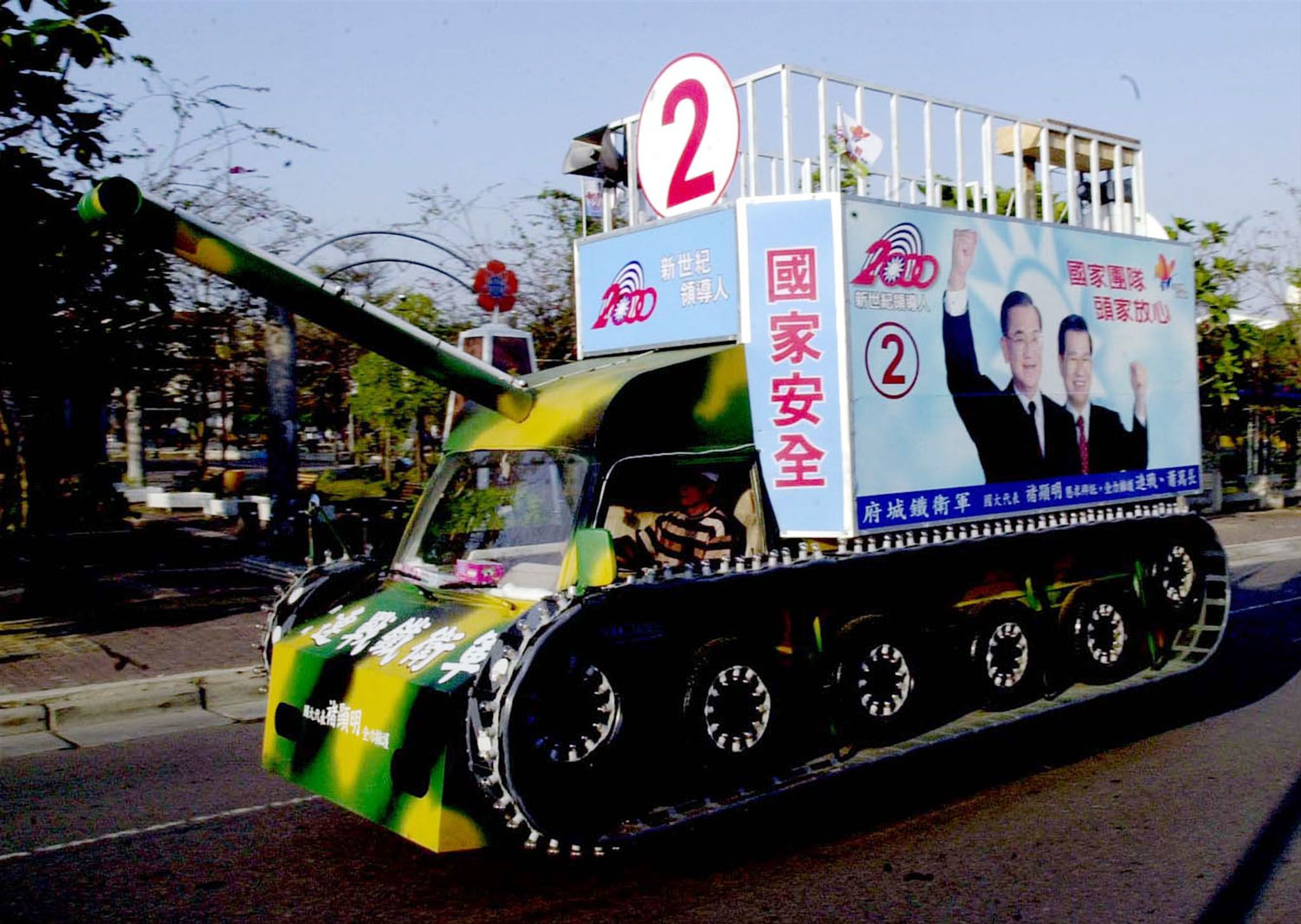 2000年3月3日，一辆军用坦克模型在台南的一条街道上游行，上面挂着国民党总统候选人连战和他的竞选伙伴萧万长的广告牌 （ SK / TAN ）