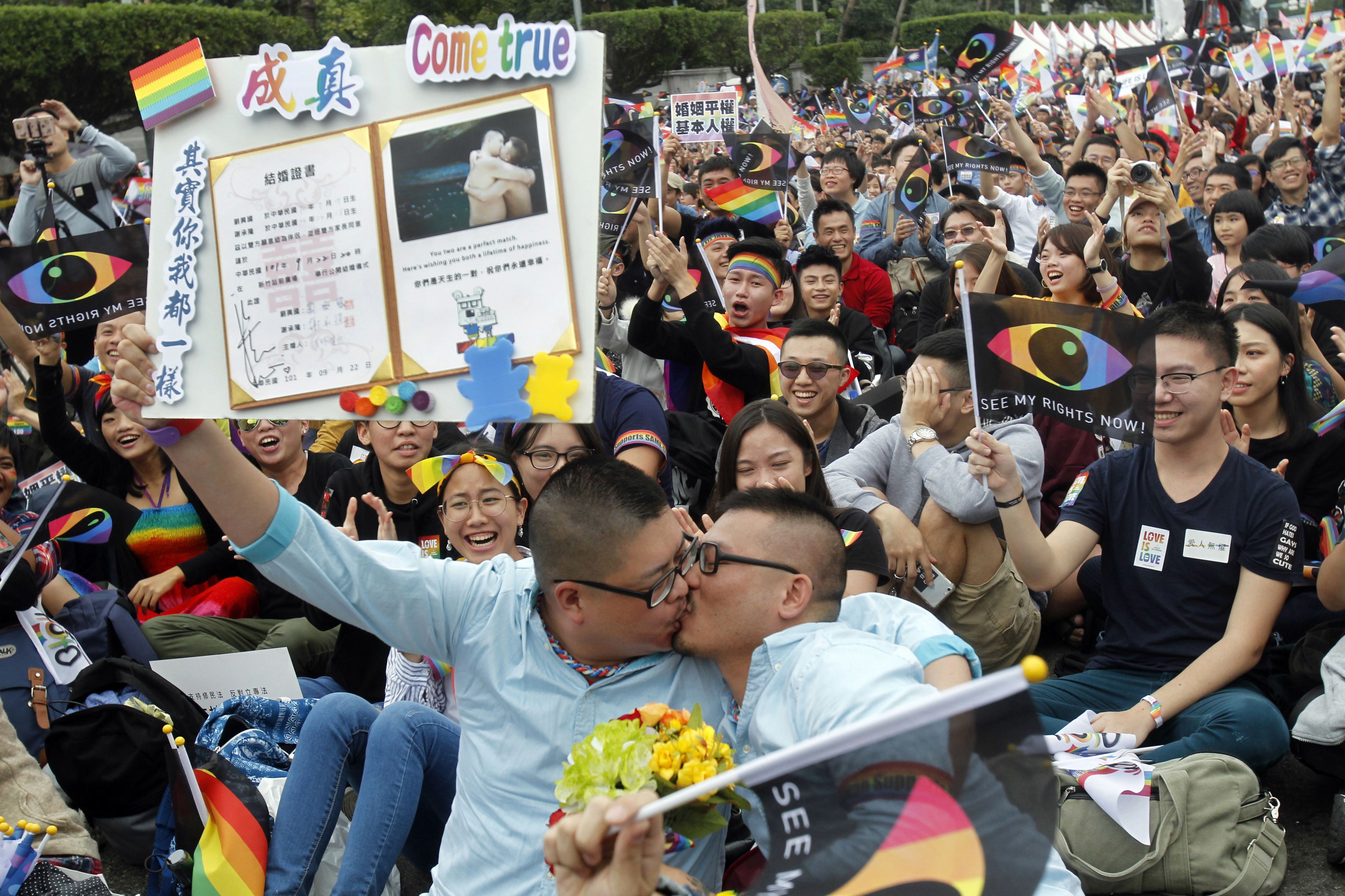 世界人权日当天，一对夫妇在台北举行的支持同性婚姻提案集会上亲吻并手持结婚证。台湾选民于 2018 年 11 月 24 日星期六进行了同性婚姻公投。
