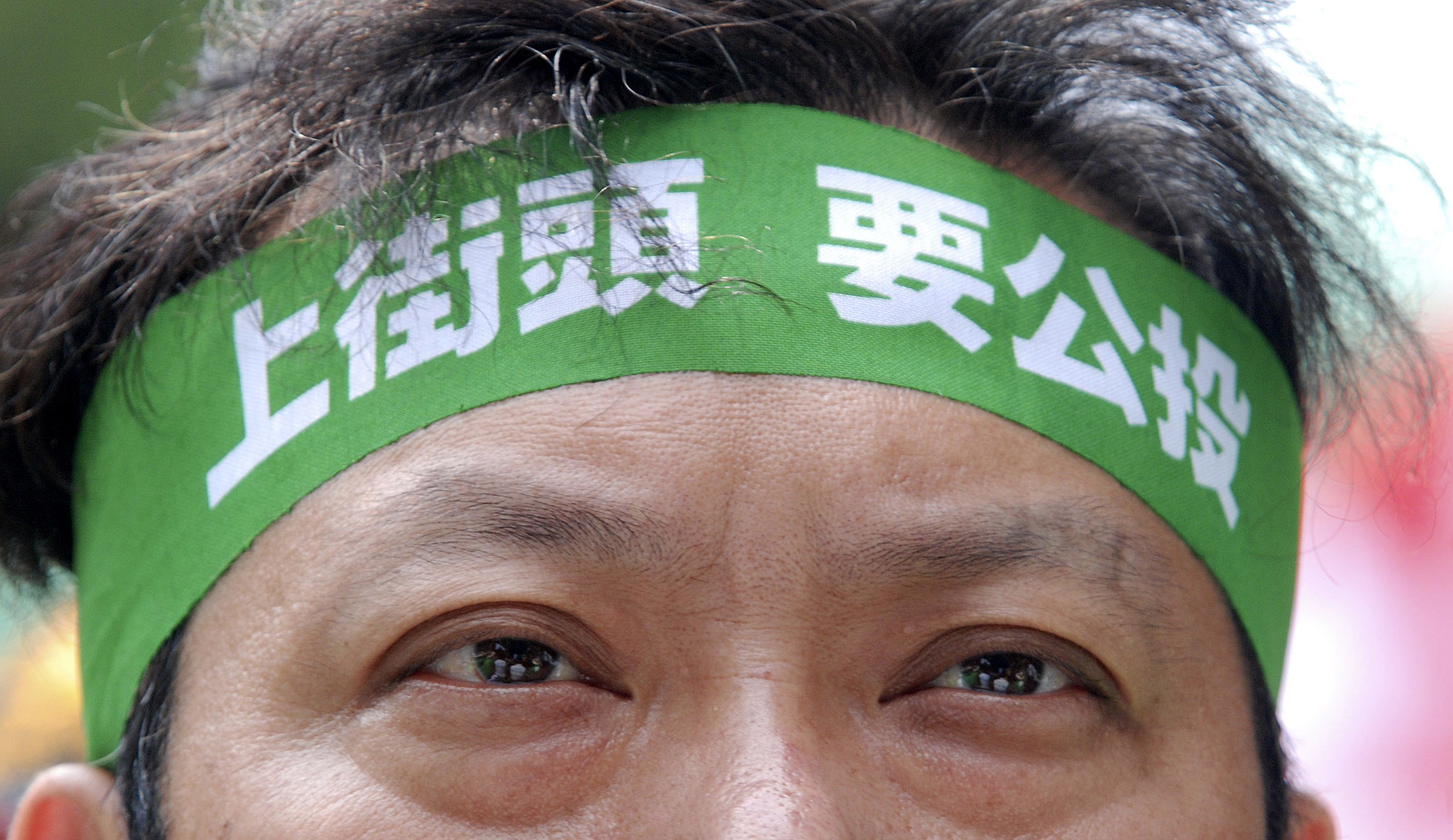 2010 年 5 月 20 日星期四，在台北立法院外静坐抗议期间，一名反对经济合作框架协议 (ECFA) 的抗议者头带上写着“上街头，要公投”。