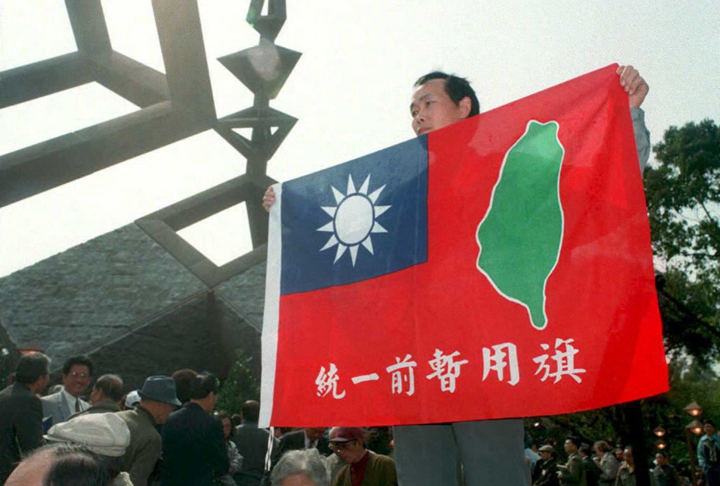 二二八紀念仪式上，台湾商人Chen Yun-ching手持結合国民党“太阳”徽和民进党“台湾岛”徽的旗帜。