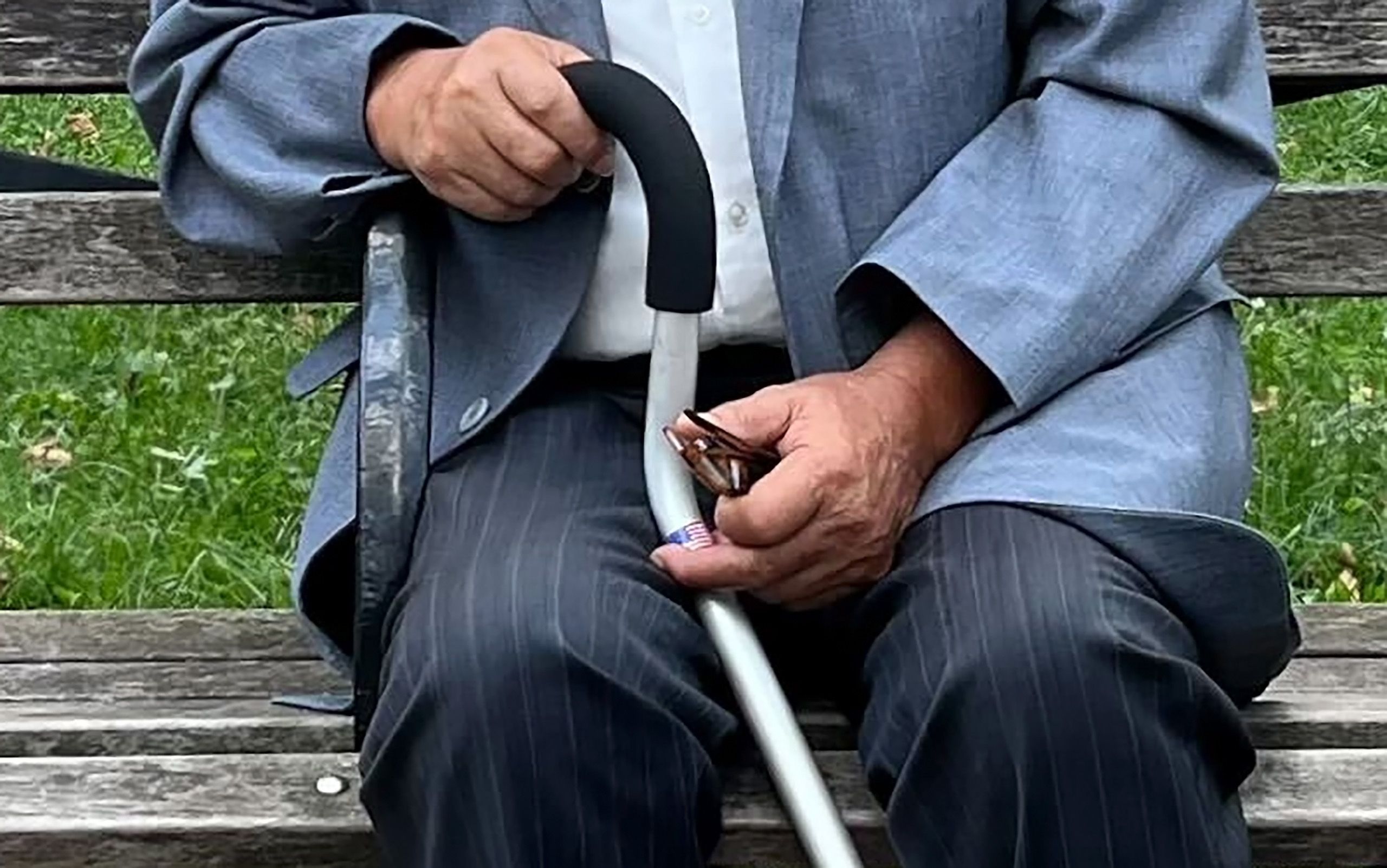 王书君拄着拐杖出庭，银色拐杖上贴着美国国旗